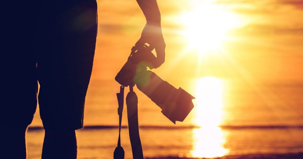 Someone holding a camera at their side with the sunset in the background